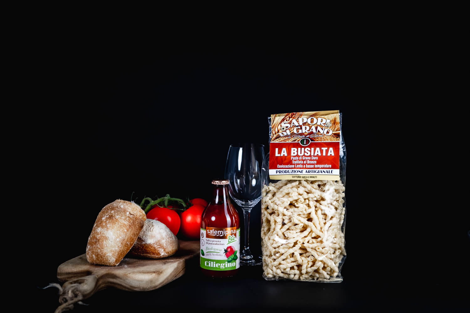Italiensk pasta, tomatsås och bröd mot en mörk bakgrund