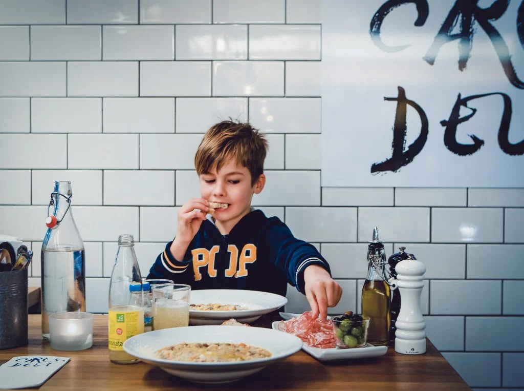 En ung gäst äter pasta vid ett bord på Carls Deli